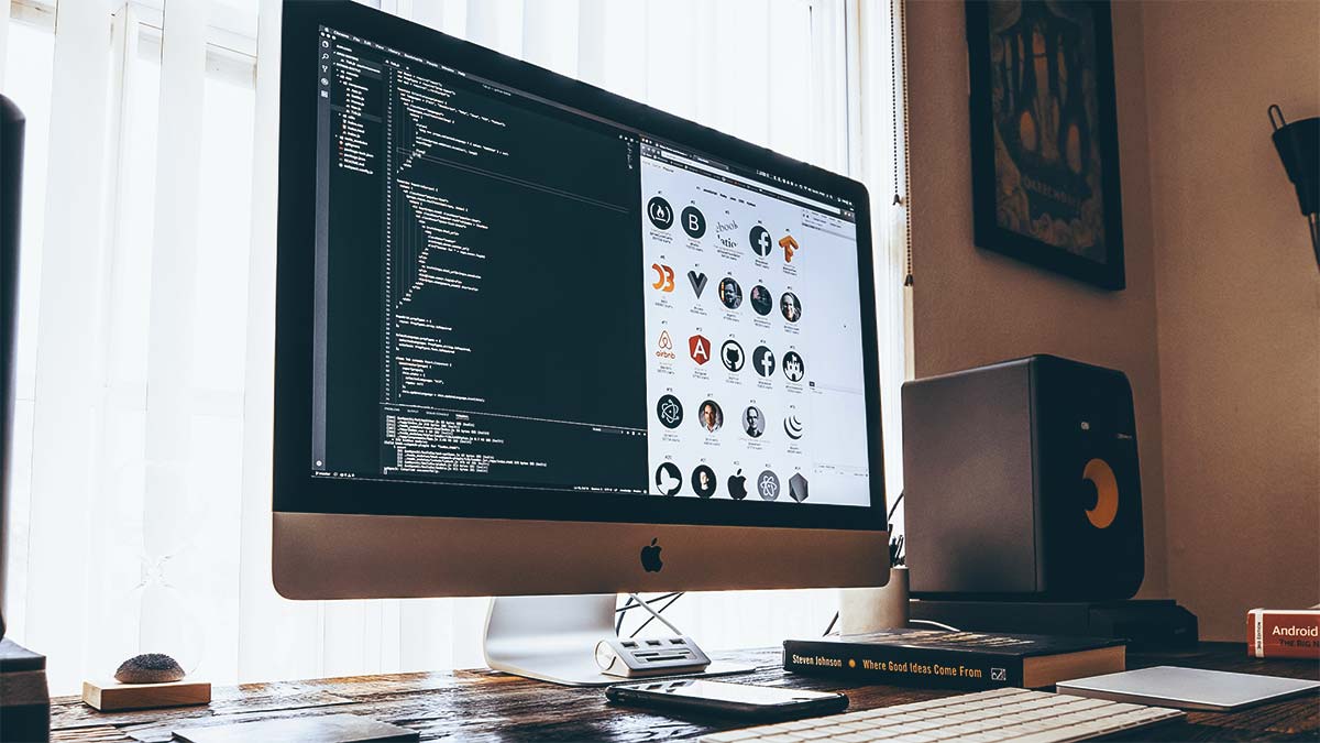 Photo d'un bureau avec un écran d'ordinateur ouvert sur un programme de développement web, avec des lignes de code.